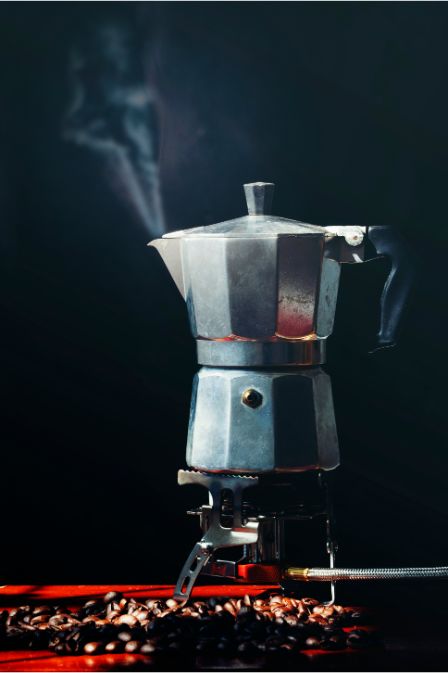 9 Bar Espresso Machine: The Secret to Café-Quality Coffee at Home 16 Moka pot brewing coffee on a stove with coffee beans around.