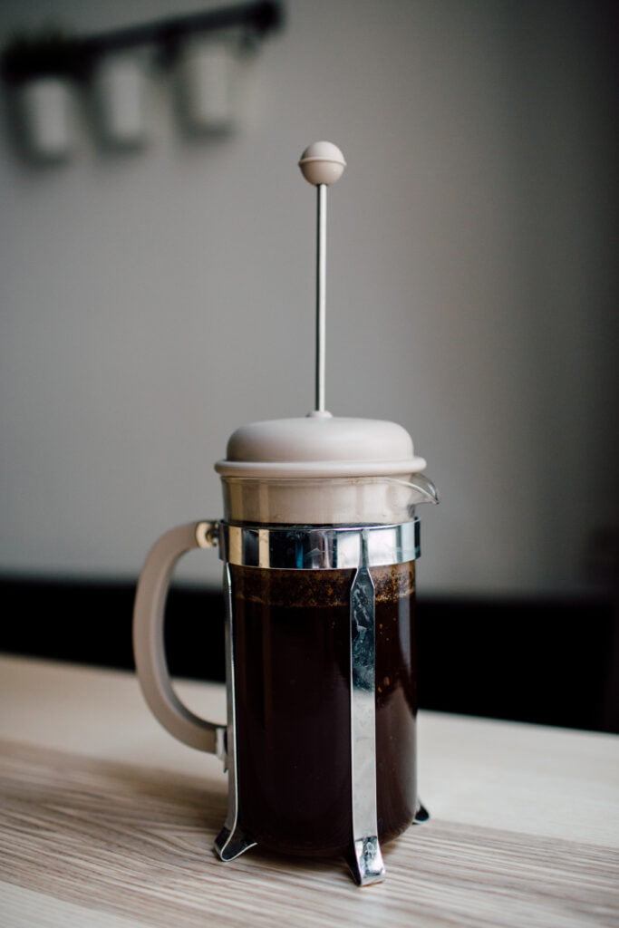 The Ultimate Guide to 12 Cup French Coffee Press Brewing 15 A French press sits on a wooden table, filled with freshly brewed coffee.