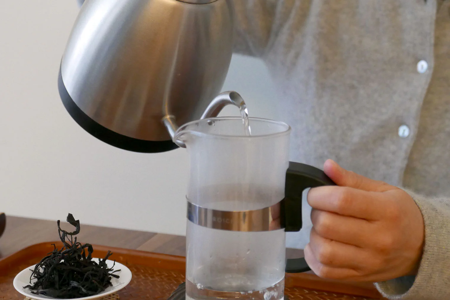 Hot water is poured from a kettle into a french press, warming the glass