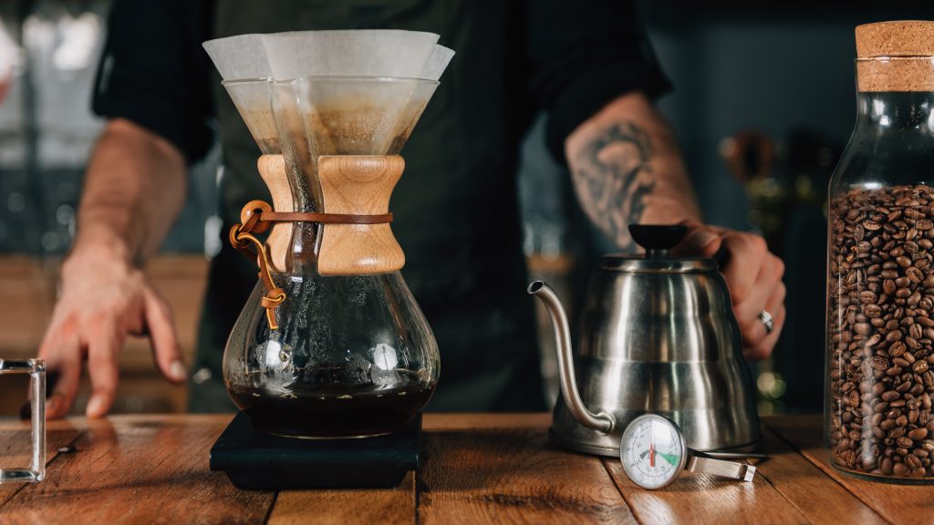 Bình Chemex với cổ ốp gỗ, cùng các dụng cụ pha chế thiết yếu.