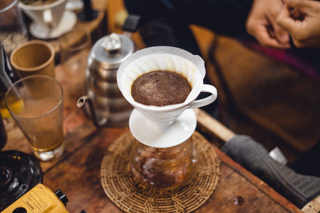 Hario V60 coffee dripper with ground coffee over a glass carafe