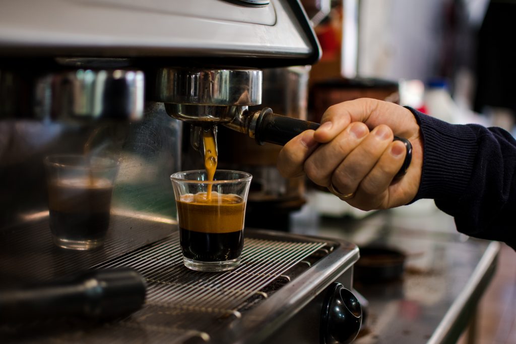 Tổng Quan về Espresso: Lịch Sử, Văn Hóa, Kỹ Thuật và Lợi Ích 15 Một máy pha Espresso hiện đại đang pha một shot cà phê vào một chiếc cốc thủy tinh.