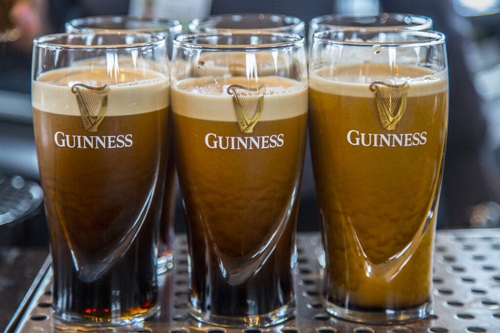 What is Nitro Coffee? The Science Behind This Creamy, Next-Level Cold Brew 8 Five freshly poured pints of Guinness beer with the iconic harp logo, known for its smooth texture and creamy head.
