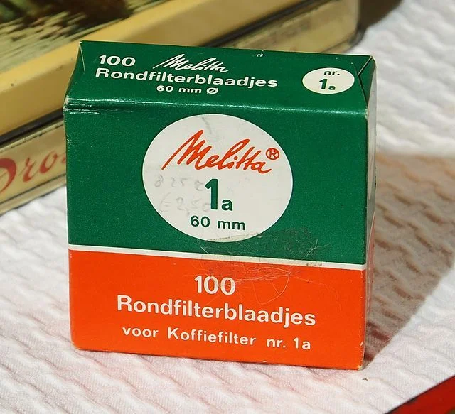 A vintage box of Melitta coffee filter papers, labeled "100 Rondfilterblaadjes voor Koffiefilter nr. 1a," with green and orange packaging.