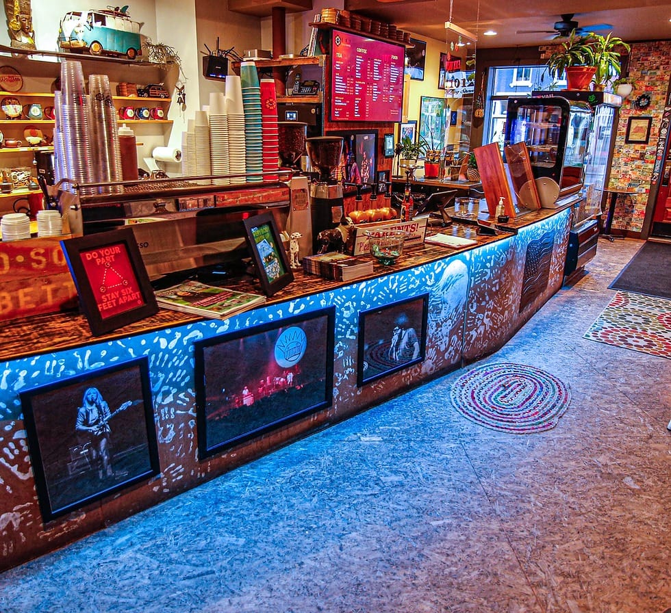 Alexandria's Ultimate Cortado Cafe & Coffee Shop Guide 2025 10 Interior view of ESP Tea & Coffee's counter area with blue neon-lit base, vintage music photographs, digital menu display, stacked colorful cups, potted plants, and retro decorations including a miniature van on wooden shelving.