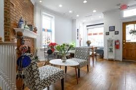 Alexandria's Ultimate Cortado Cafe & Coffee Shop Guide 2025 12 Bright, welcoming cafe interior with exposed brick wall, geometric-patterned armchairs, hardwood flooring, potted plants, and large windows bringing in natural light, showcasing Turkish Coffee Lady's modern interpretation of a traditional coffee house.