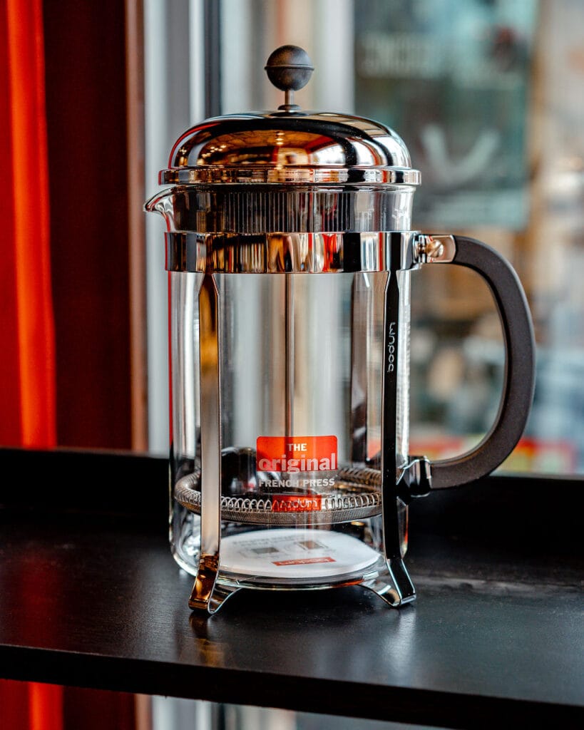The Ultimate Guide to 12 Cup French Coffee Press Brewing 18 12 cup Bodum Chambord French press with chrome finish and black handle on dark counter, showing iconic design and red original label