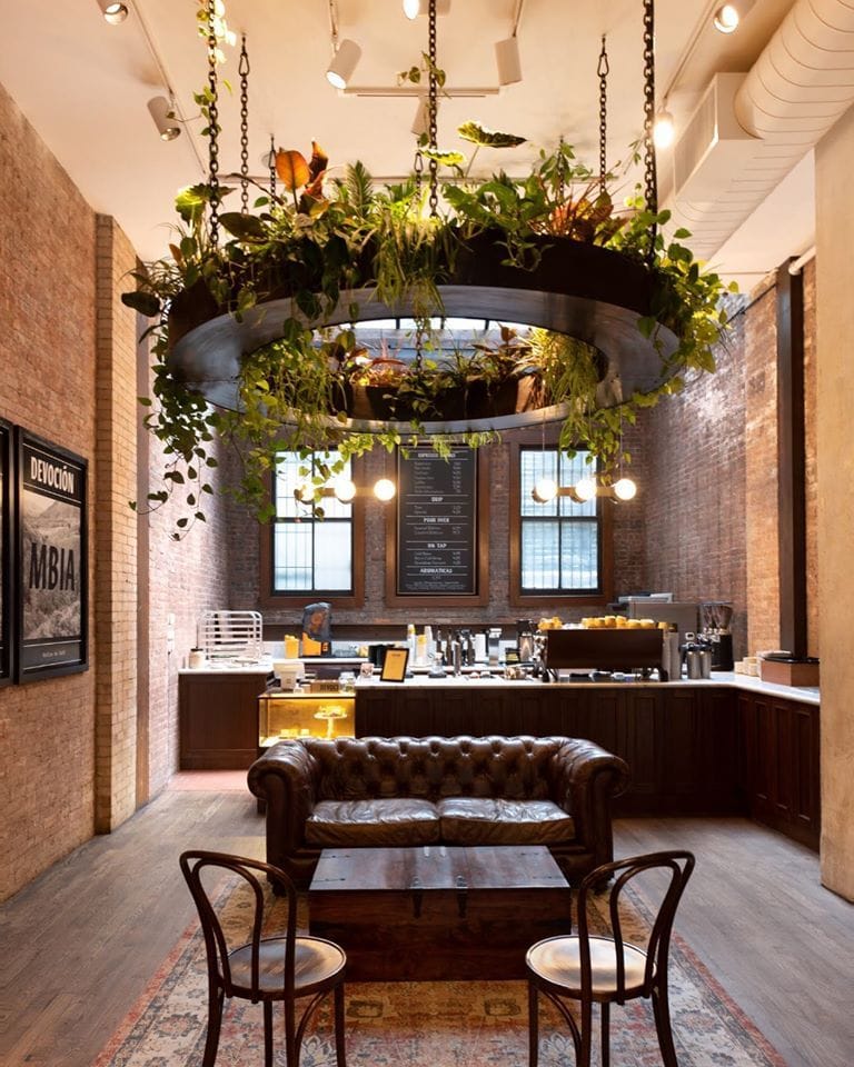 Finding Your Perfect Coffee Shop Near Me: A Blend of Beans, Brews, and Belonging 6 Devoción coffee shop interior in Brooklyn featuring industrial brick walls, leather sofa, chic plant chandelier, and cozy seating.