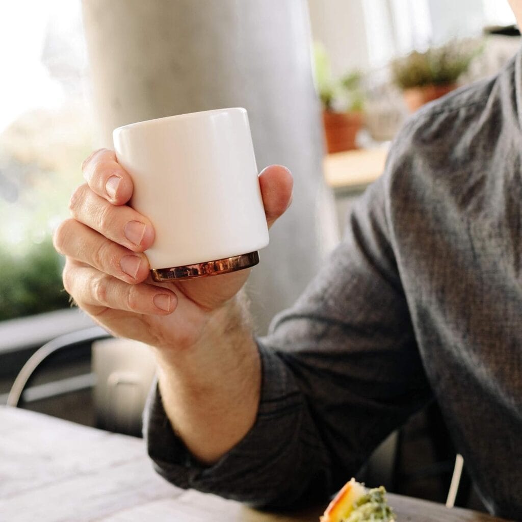 Finding Perfect Cortado Cup: A Journey Worth Taking 15 Person holding Fellow Monty Milk Art Cup in matte white with distinctive copper base against natural window lighting