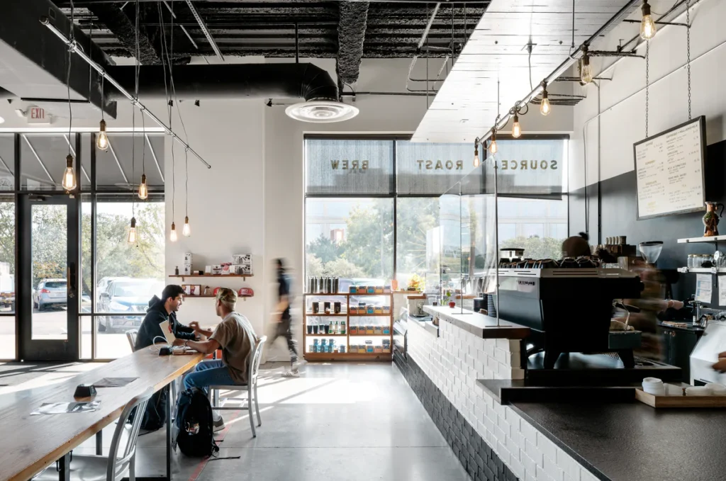 Finding Your Perfect Coffee Shop Near Me: A Blend of Beans, Brews, and Belonging 7 Interior of Merit Coffee in Austin, TX, featuring minimalist industrial design, bright natural lighting, and patrons enjoying coffee at communal tables.