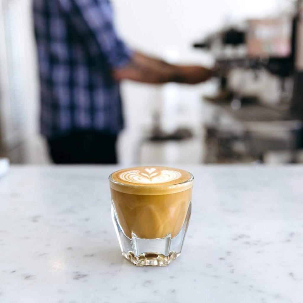 Finding Perfect Cortado Cup: A Journey Worth Taking 14 notNeutral Vero 4.25oz clear glass with cortado and latte art on marble countertop, barista in background