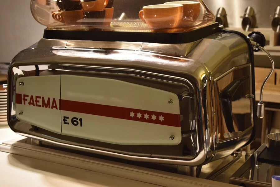 The 1970s Coffee Machine Revolution: Old Style Machines & Vintage Brewing Legacy 8 Vintage FAEMA E61 espresso machine with chrome finish and amber cups, an iconic model from the 1970s coffee machine revolution