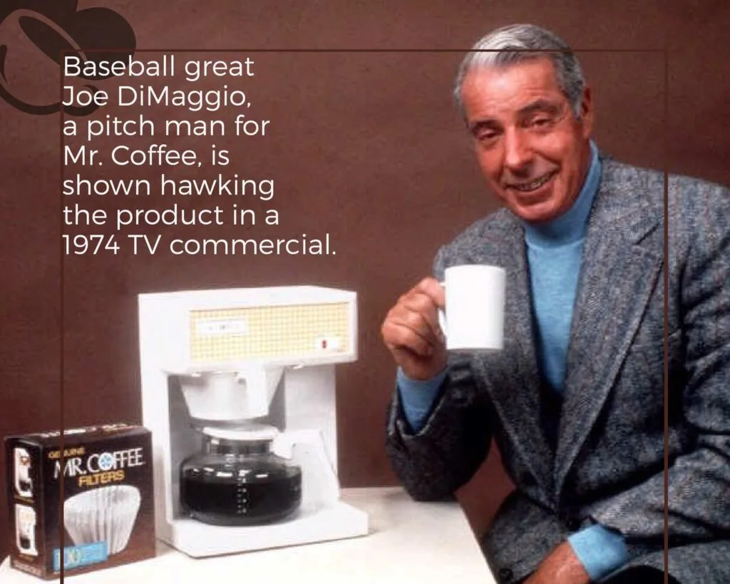 Baseball legend Joe DiMaggio endorsing the revolutionary Mr. Coffee automatic drip coffee maker in a 1974 TV commercial, showing the white appliance, filter box, and holding a cup of freshly brewed coffee