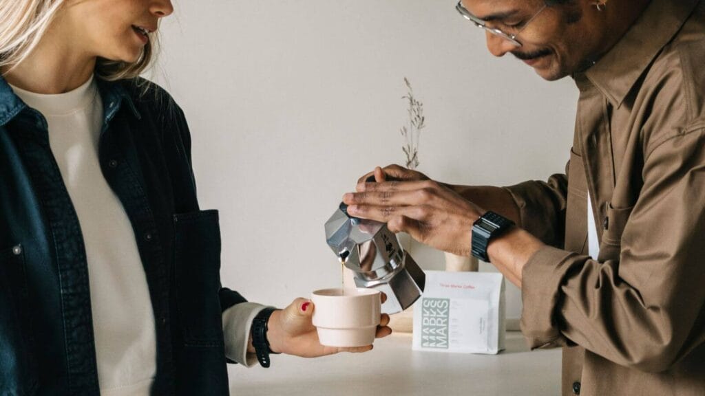 Coffee being poured from a Moka pot into a pink Three Marks 185 Marks cup, showcasing its unique geometric design for flat white cups.