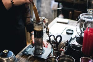Barista stirring coffee during critical Aeropress brew time phase, ensuring even extraction with wooden paddle