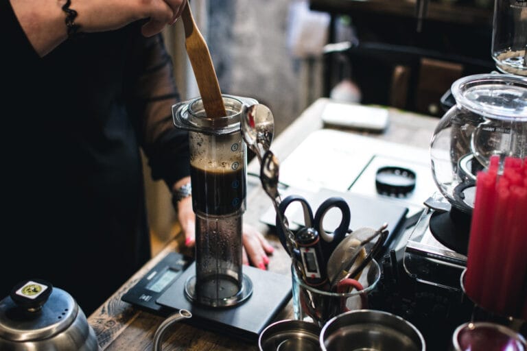 Barista stirring coffee during critical Aeropress brew time phase, ensuring even extraction with wooden paddle