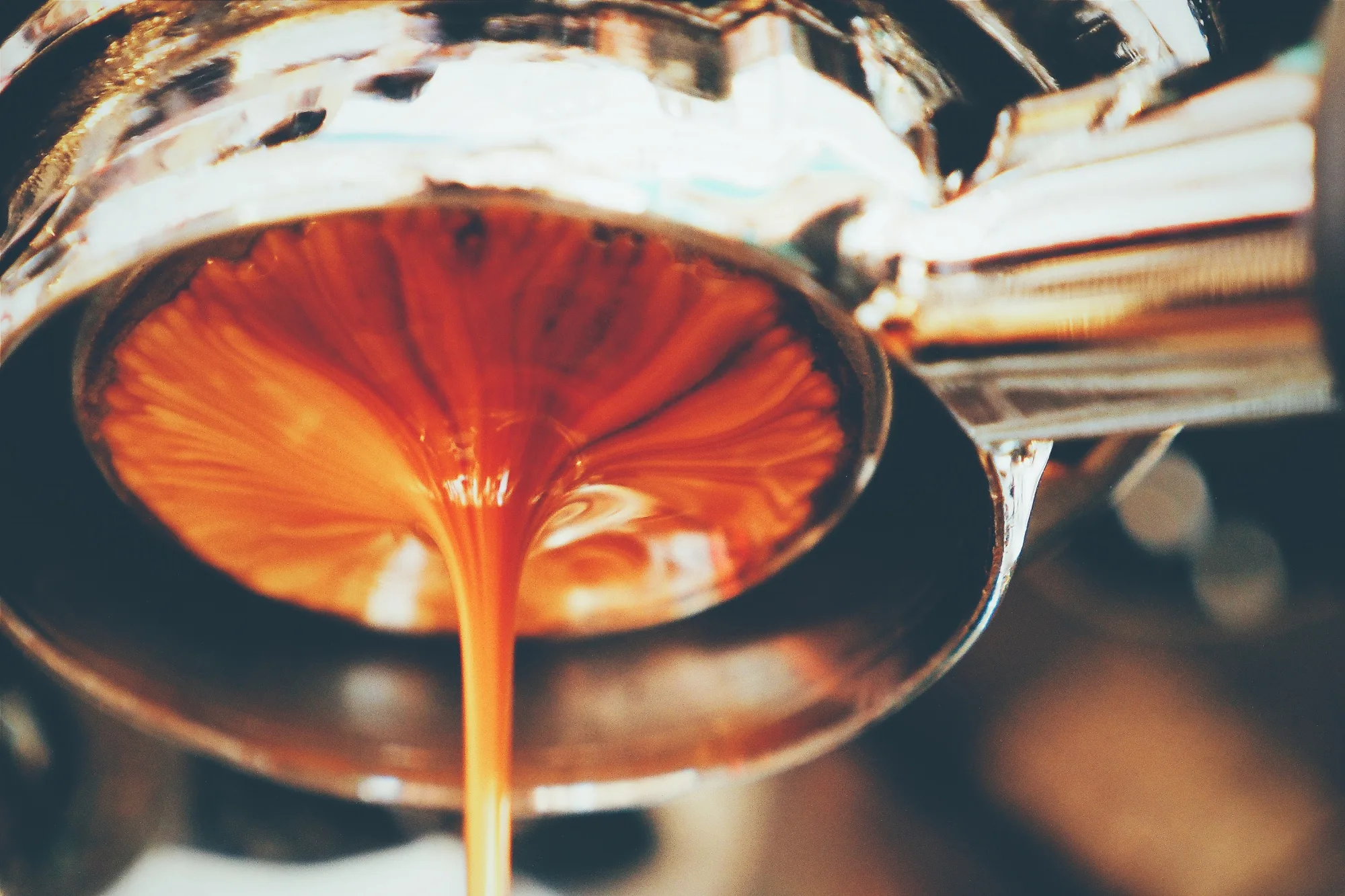 Fresh espresso extraction with golden crema flowing from portafilter, showing perfect results from quality beans for espresso