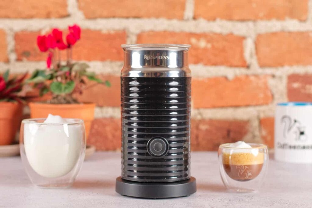 Aeroccino Milk Frother Secret Of Perfect Home Café Foam 5 Nespresso Aeroccino 3 milk frother displayed with a glass of frothed milk and espresso against a brick wall background
