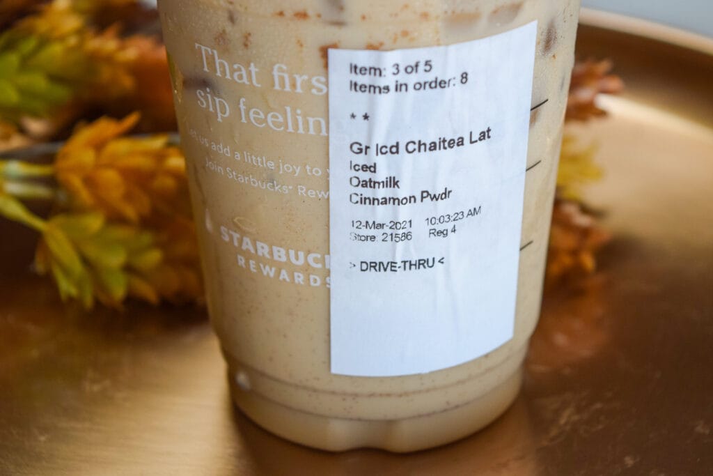 Starbucks iced chai latte with oatmilk and cinnamon powder showing drink label, contains moderate amount of caffeine compared to coffee-based beverages