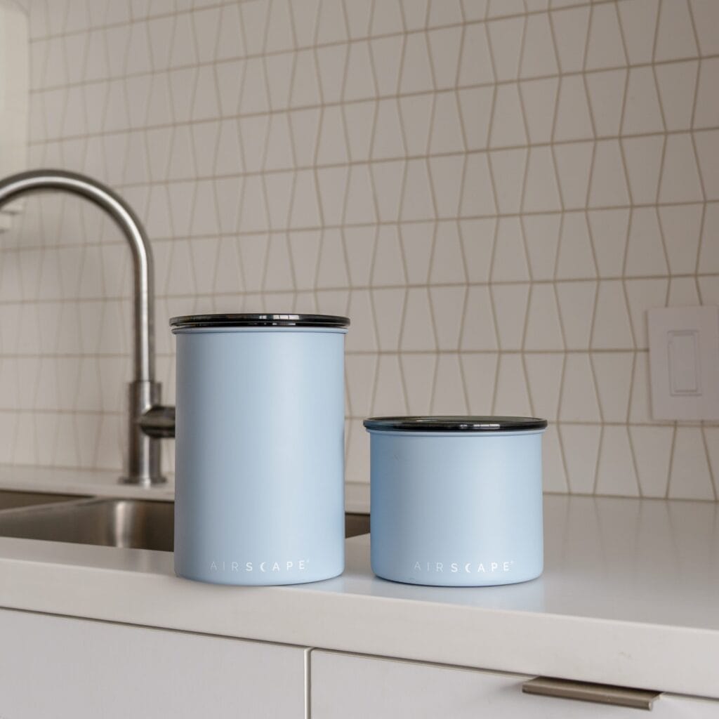 Airscape Coffee Canister: The Revolutionary Technology That Locks in Coffee Freshness 13 Two Airscape coffee canisters in light blue that actively remove and lock out air to preserve freshness and flavor, displayed in a modern kitchen