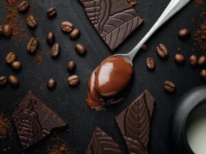 Melted chocolate in spoon with coffee beans and chocolate pieces showing mocha vs chocolate ingredients comparison