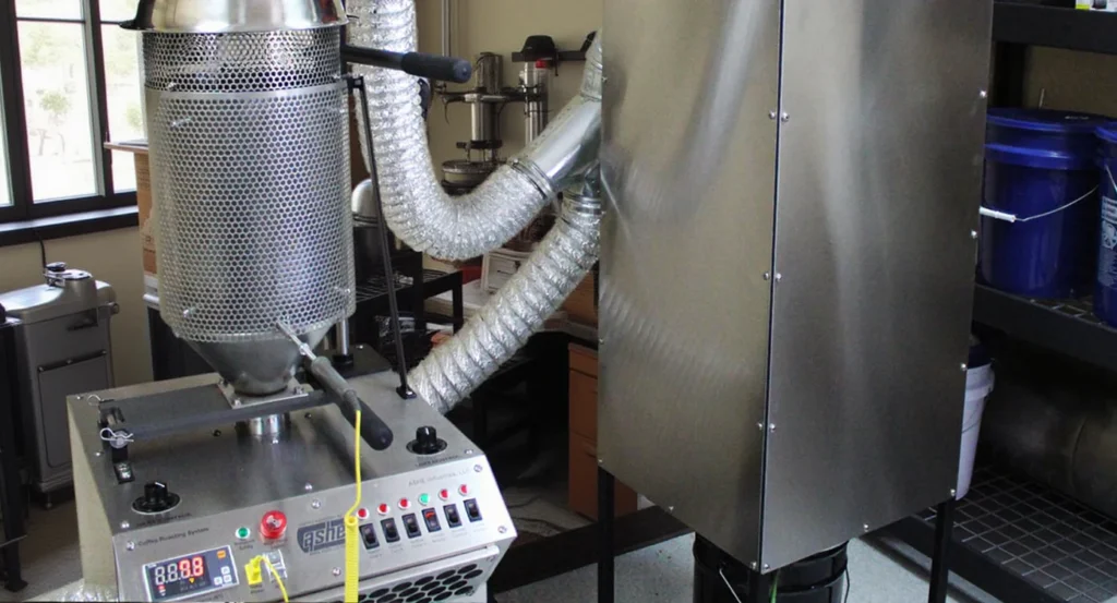 Modern fluid bed roaster machine in a coffee roasting facility with control panel and ventilation system