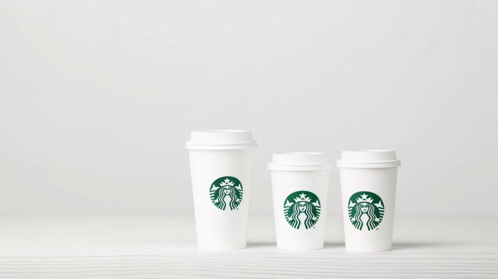 Three Starbucks hot cups visually demonstrating the size difference between the Tall, Grande, and Venti options for understanding Starbucks drink sizes.