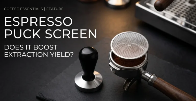 A shiny metallic espresso puck screen placed on a portafilter filled with coffee grounds, next to a modern minimalist tamper on a dark slate background.