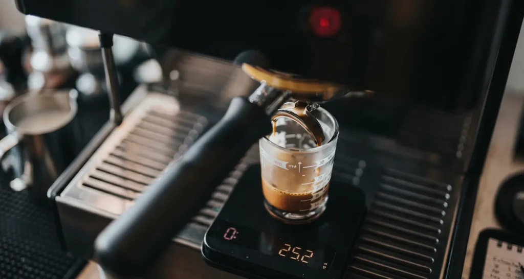 Espresso machine extracting a shot into a cup on a scale.
